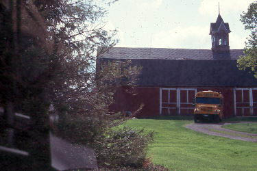 Barn with a school bus in front of it